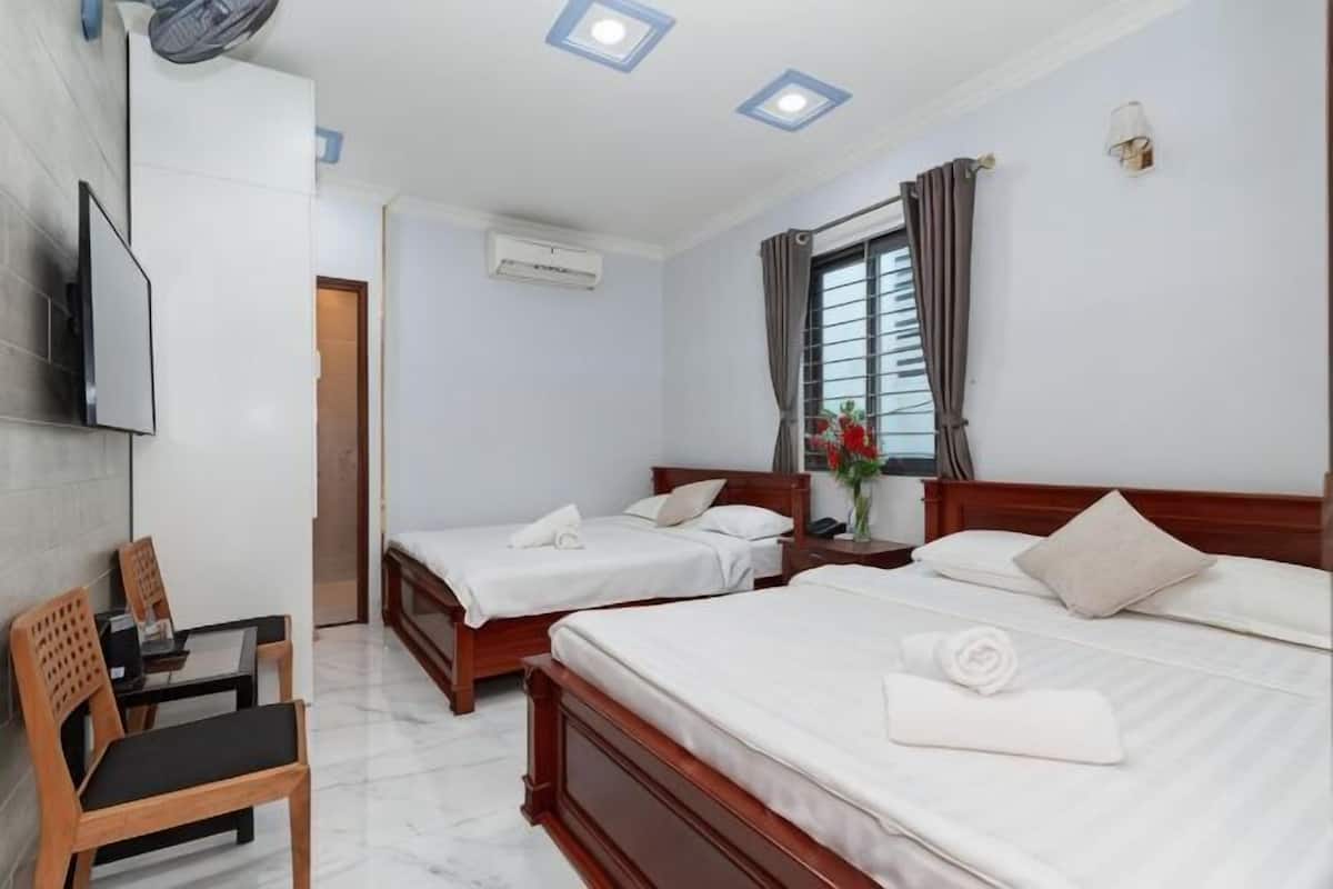 Ein Hotelzimmer mit zwei Betten, einem Fernseher, einem Schreibtisch und einem Sessel.