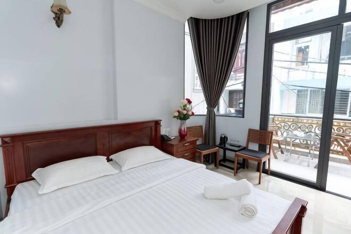 Ein Hotelzimmer mit einem großen Bett, einem Schreibtisch, einem Stuhl und Blick ins Freie.