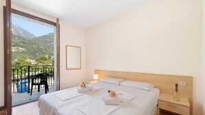 A hotel room with two beds, a balcony with a chair, and a nightstand with a bottle. - Porto Letizia Como 9, Porlezza, Italy (Porlezza)