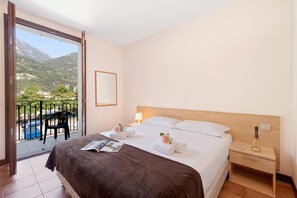 A hotel room with a bed, a nightstand, a reading area, and a balcony with a view of mountains. - Porto Letizia Como 9, Porlezza, Italy (Porlezza)