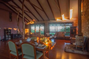Una sala de estar acogedora con chimenea, vigas de madera y ventanas amplias que dan a vistas del exterior.
