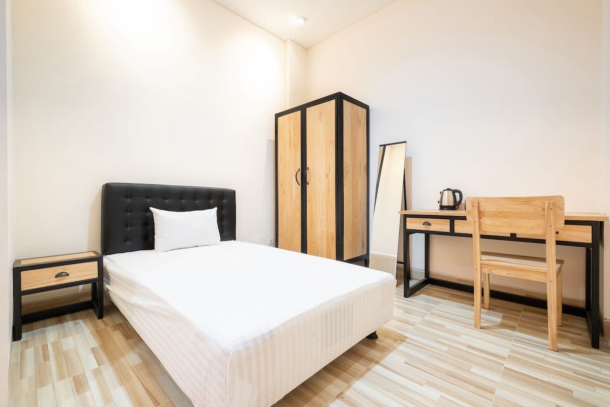 Un dormitorio con cama, mesita de noche, armario, escritorio, silla y espejo.