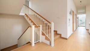 A spacious interior with a wooden staircase and a long hallway. - OYO Life 2801 Sari Panguripan (Kos Putri & Pasutri) (Depok)