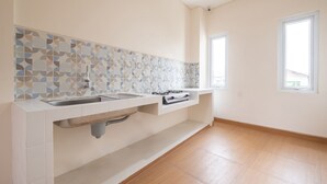 A modern kitchen with a tiled backsplash, a built-in sink, and a window providing natural light. - OYO Life 2801 Sari Panguripan (Kos Putri & Pasutri) (Depok)