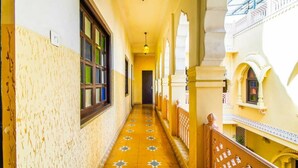 Un couloir au sol décoré de motifs, un escalier et des éléments architecturaux traditionnels.