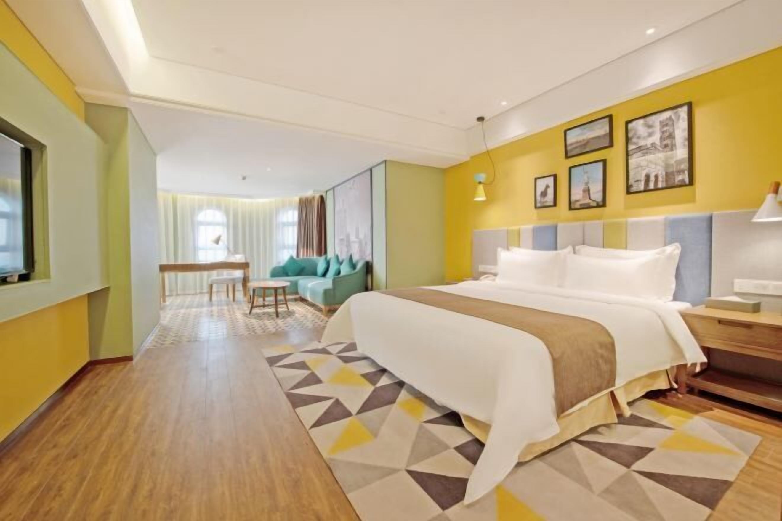 A hotel room with a bed, a desk, a chair, a sofa, and a window.