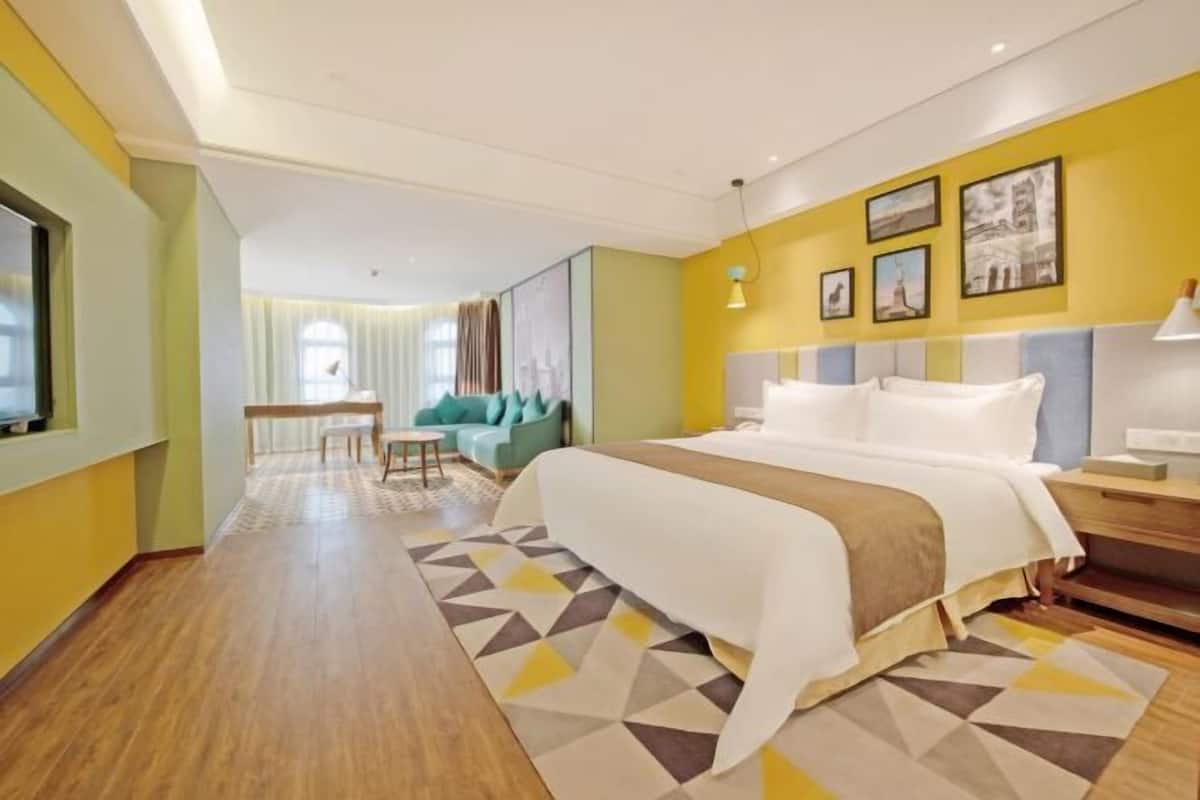 Een hotelkamer met een bed, een bureau, een stoel, een bank en een raam.