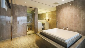 A modern bathroom with a large bathtub, a glass shower enclosure, and a tiled floor.