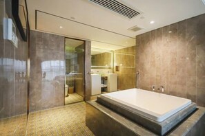 Ein modernes Badezimmer mit einer großen Badewanne, einer Duschkabine aus Glas und einem gefliesten Boden.