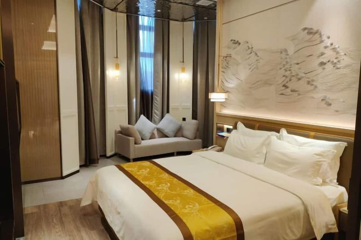 Een hotelkamer met een bed, een bank, een nachtkastje en een muur met kunst.