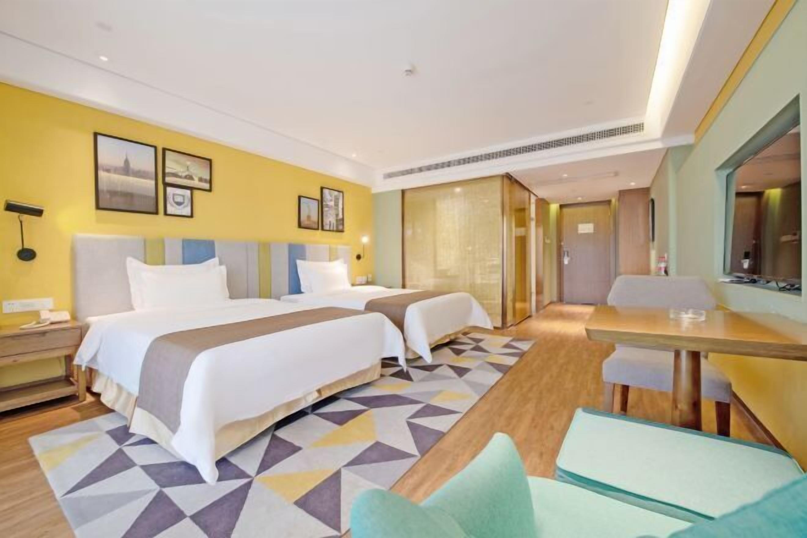 A hotel room with two beds, a dining table, and a small seating area.