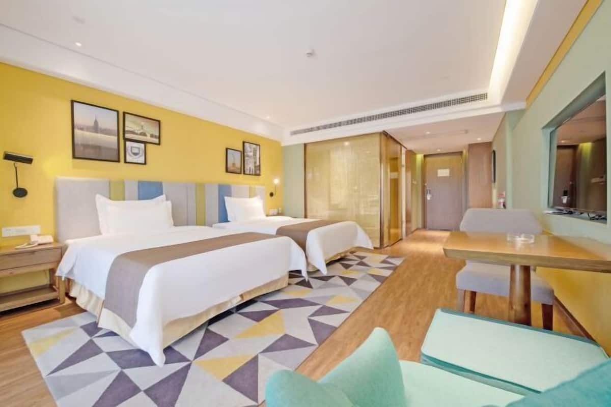 Een hotelkamer met twee bedden, een eettafel en een zithoekje.