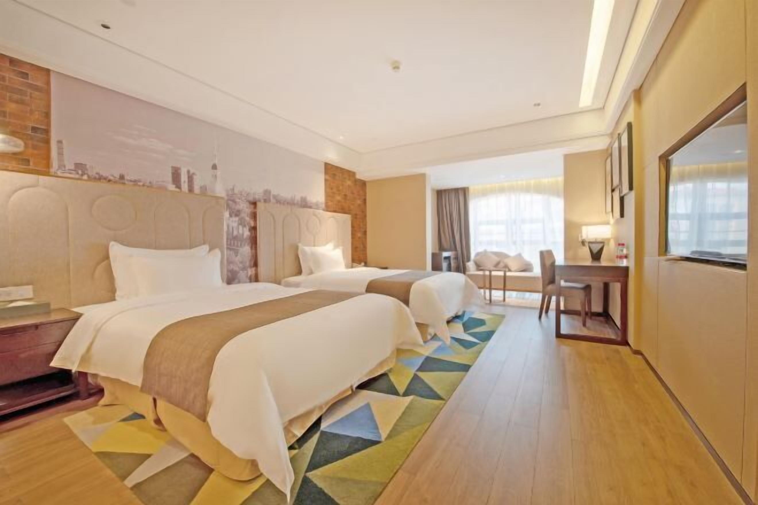 A hotel room with two beds, a desk, and a chair.