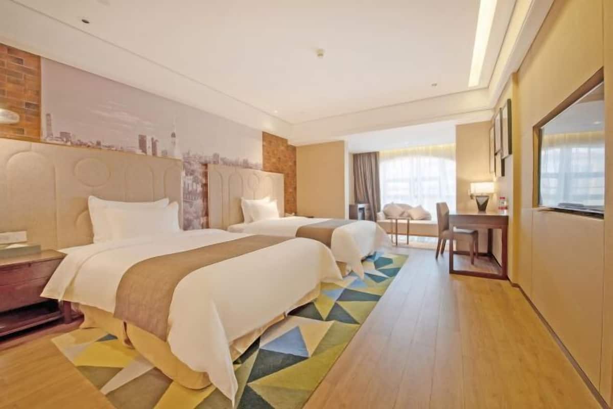 Een hotelkamer met twee bedden, een bureau en een stoel.