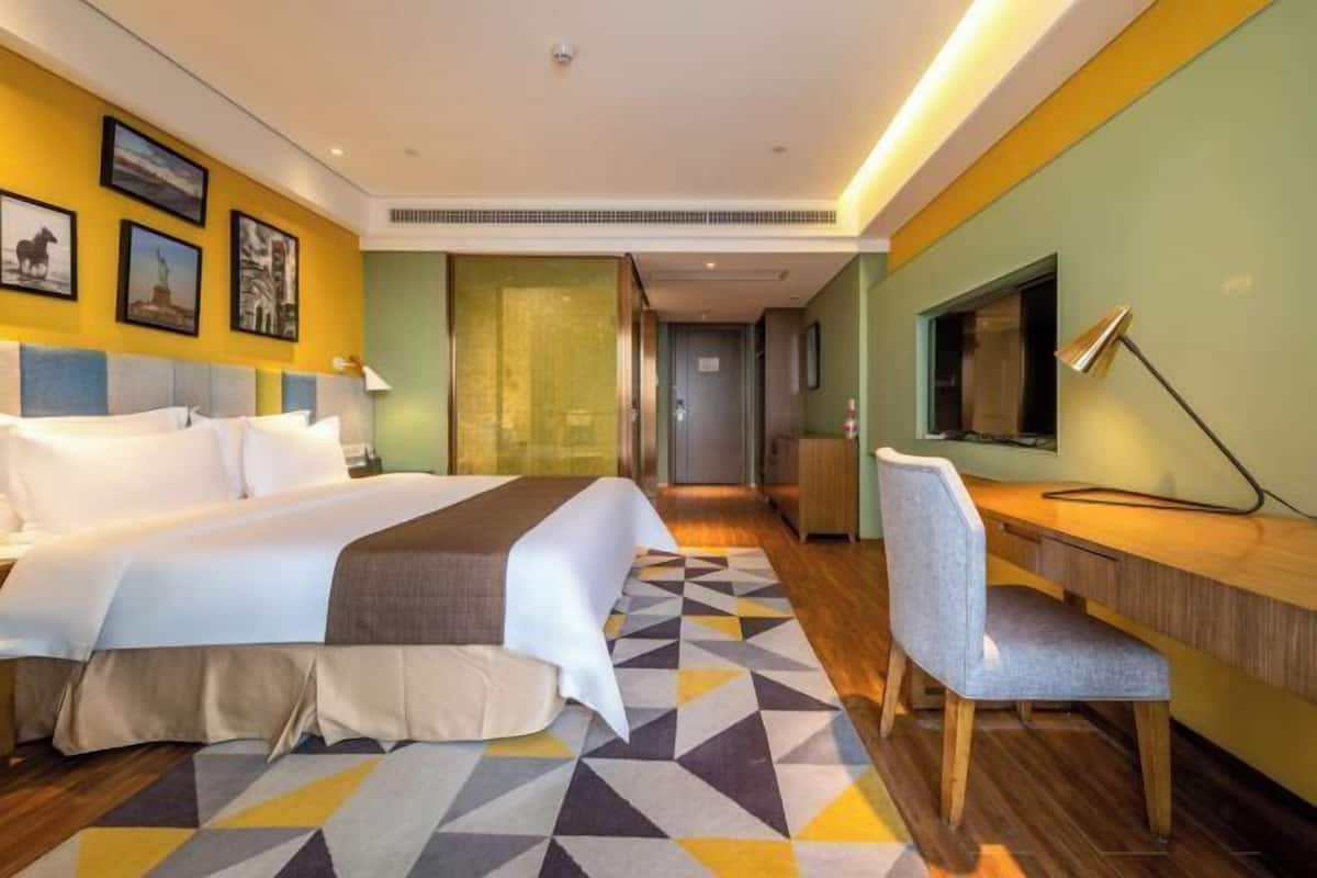 Een hotelkamer met een bed, bureau, stoel en een televisie.