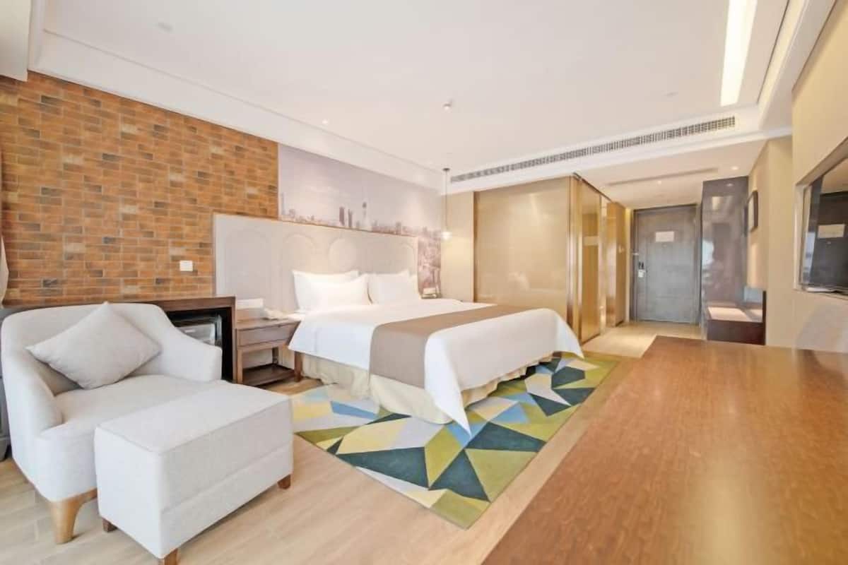 Een moderne hotelkamer met een bed, een bank, een bureau en een televisie.
