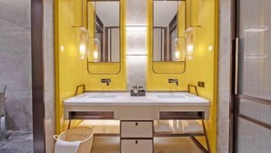 A bathroom with a double sink, two mirrors, and a small wicker basket.