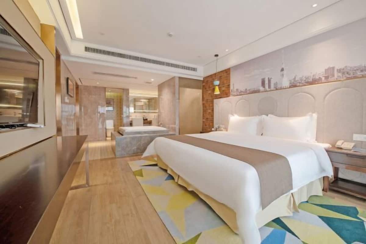 Een hotelkamer met een groot bed, een bureau, een stoel, een nachtkastje en een stadsgezicht muurschildering.