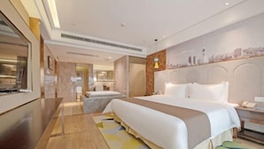 A hotel room with a large bed, a desk, a chair, a nightstand, and a cityscape mural on the wall.