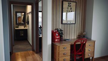 A study room with a wooden desk, a red chair, a framed eye chart on the wall, and a mirror above the desk.