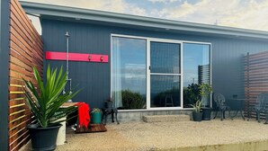 A modern house with a large window, a wooden fence, and potted plants. - Mount View Accommodation Marrawah (Marrawah)