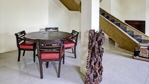 Een eetruimte met een ronde tafel en stoelen, een trap en een decoratief houten beeldhouwwerk.