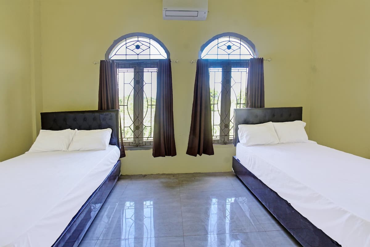 Una habitación con dos camas, piso de baldosas y una ventana con cortinas.