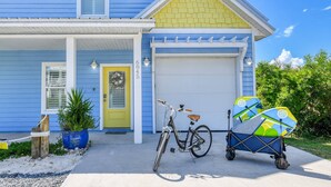 A house with a yellow door, a bicycle, and a stroller with surfboards. - Bougainvillea Beach Bungalow (St. Augustine)