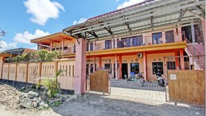 A two-story building with a covered entrance and a gated driveway. - OYO Life 92847 Penginapan Muslim Walker (Praya)