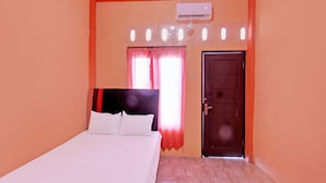 A bedroom with a bed, a window with curtains, an air conditioning unit, and a door. - OYO Life 92847 Penginapan Muslim Walker (Praya)
