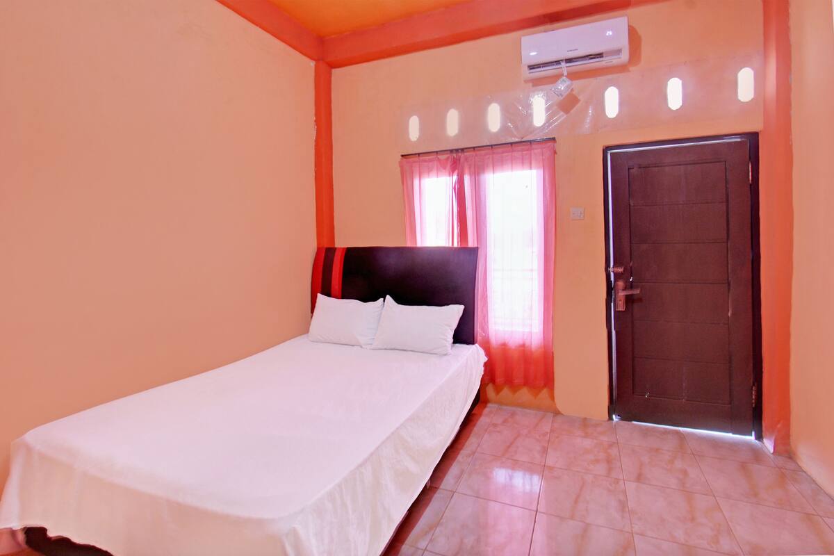 A bedroom with a bed, a door, and an air conditioning unit.