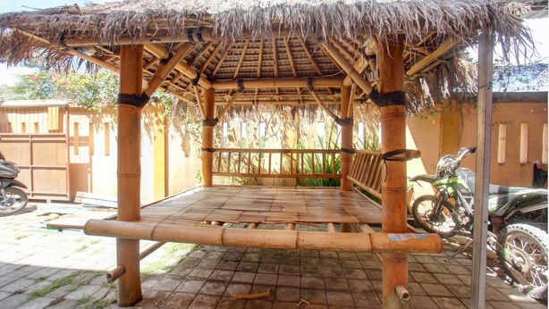 A bamboo structure with a thatched roof, a bench, and a motorcycle parked nearby. - OYO Life 92847 Penginapan Muslim Walker (Praya)