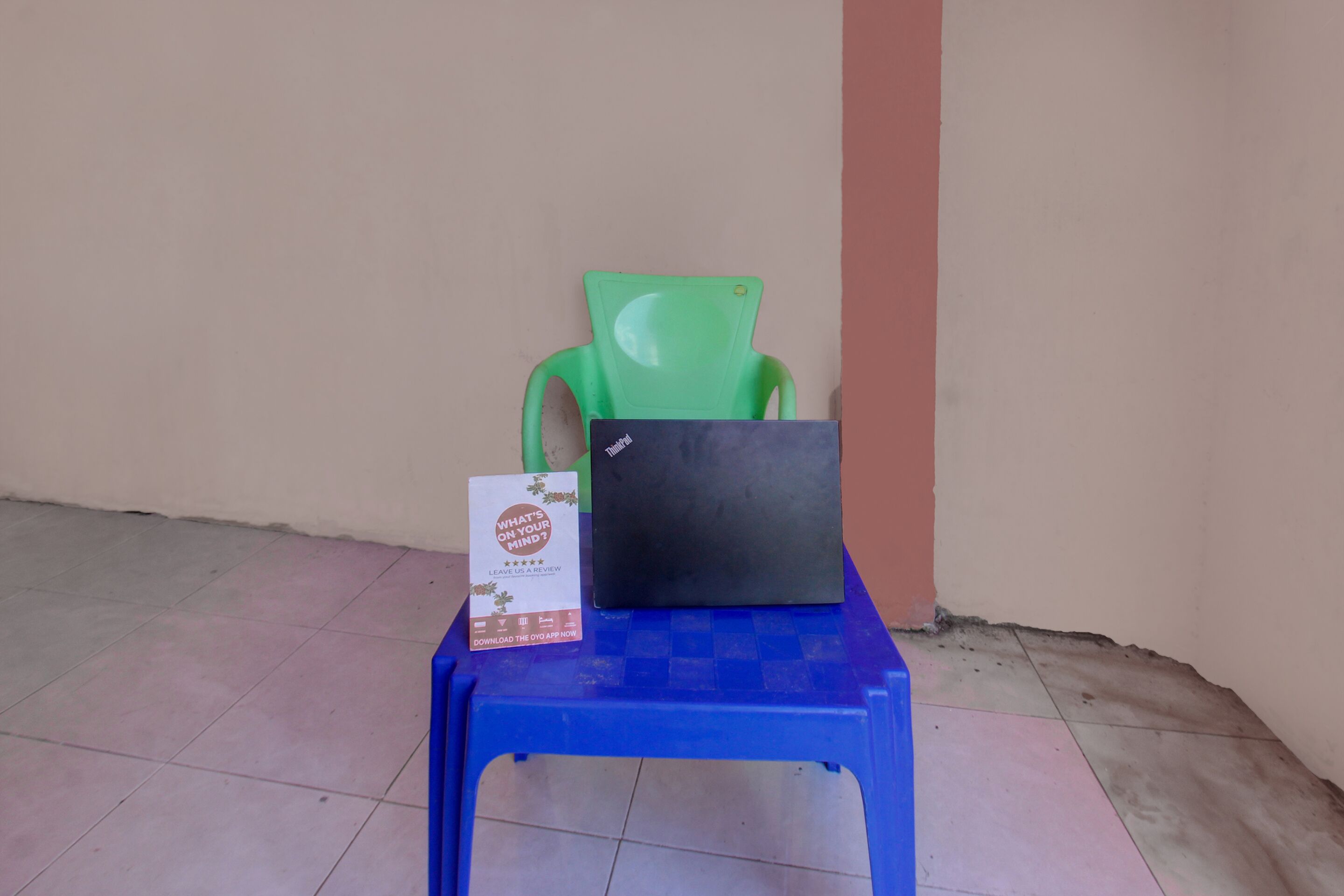 A blue plastic table with a black laptop and a brochure on it.