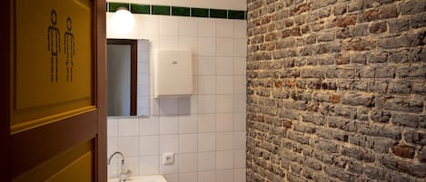 Une salle de bain avec un lavabo blanc, un miroir et un distributeur de savon fixé au mur.