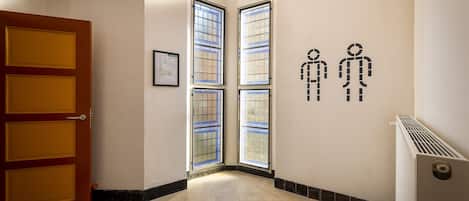 Un pasillo con una puerta roja, ventanas amplias y un radiador.
