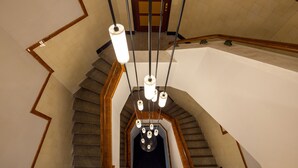 A staircase with a wooden handrail and a modern light fixture with multiple bulbs. - Stadsherberg Ald Weishoès (Venlo)