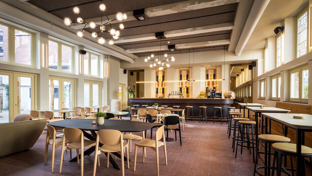 A spacious dining area with high ceilings, large windows, and a variety of seating arrangements including tables and chairs. - Stadsherberg Ald Weishoès (Venlo)
