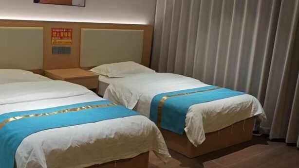 Ein Hotelzimmer mit zwei Betten, einem Kopfteil, einem Nachttisch und einem Vorhang.
