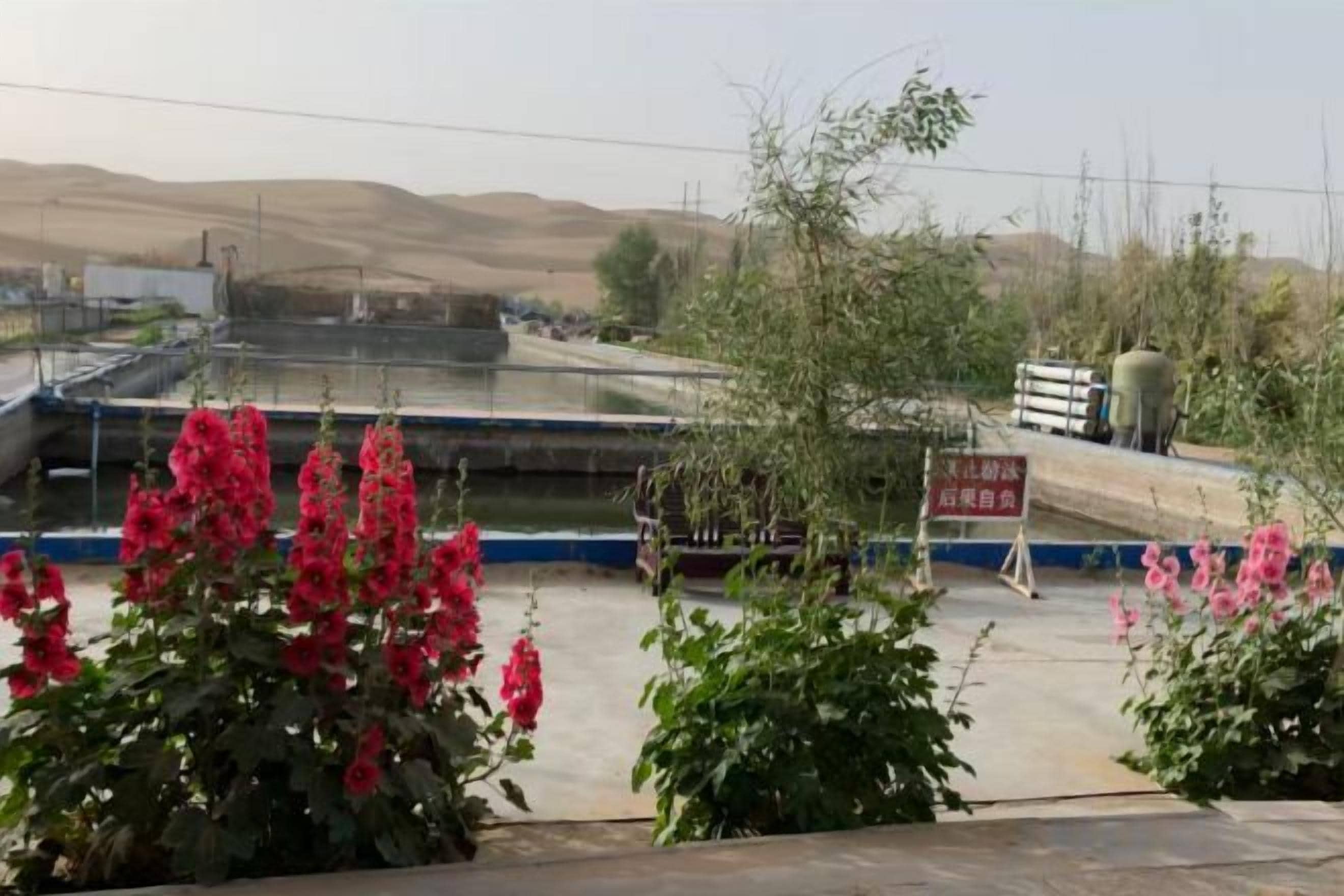 A view of a water treatment facility with industrial structures and a signboard.