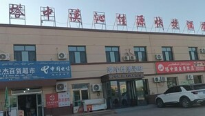 A building with multiple signs, including one for a hotel and another for a telecommunications company. - Qiemo Tazhong Town Moqin Jiayuan Express Hotel (Qiemo)