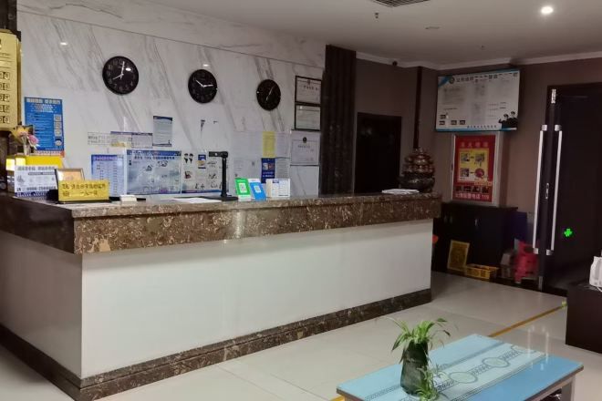 A reception desk with a marble countertop, clocks, and informational posters.