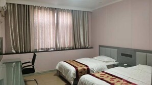 Ein Hotelzimmer mit zwei Betten, einem Schreibtisch und einem Stuhl.
