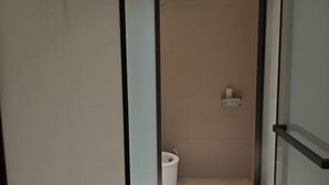 A narrow hallway leading to a toilet with a white wall and a small shelf with a roll of toilet paper. - Qiemo Tazhong Town Moqin Jiayuan Express Hotel (Qiemo)