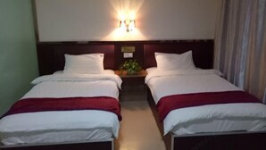 Ein Hotelzimmer mit zwei Einzelbetten, einem Nachttisch mit Pflanze und einer Wandleuchte.