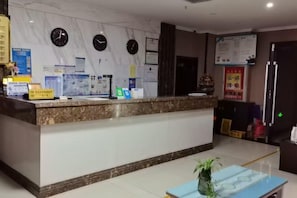 A hotel reception area with a marble counter, clocks, and informational posters. - Qiemo Tazhong Town Moqin Jiayuan Express Hotel (Qiemo)