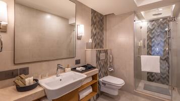 Un baño moderno con un espejo grande, un lavamanos, un inodoro y una zona de ducha.