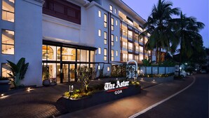 Un hotel llamado "The Astor" en Goa con fachada moderna, ventanas amplias y una entrada bien iluminada.