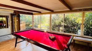 A pool table in a room with large windows and wooden floors. - The Farm House
 (Possum Brush)