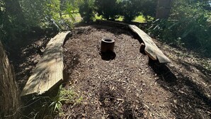 A garden area with a central compost bin surrounded by mulch, bordered by wooden logs. - The Farm House
 (Possum Brush)