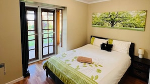 A bedroom with a bed, a painting of a tree, and a view through a door. - The Farm House
 (Possum Brush)